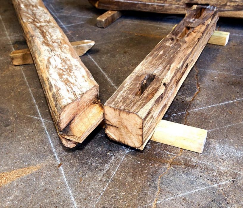 Assemblage artisanal de poutres en bois ancien pour rénover une charpente