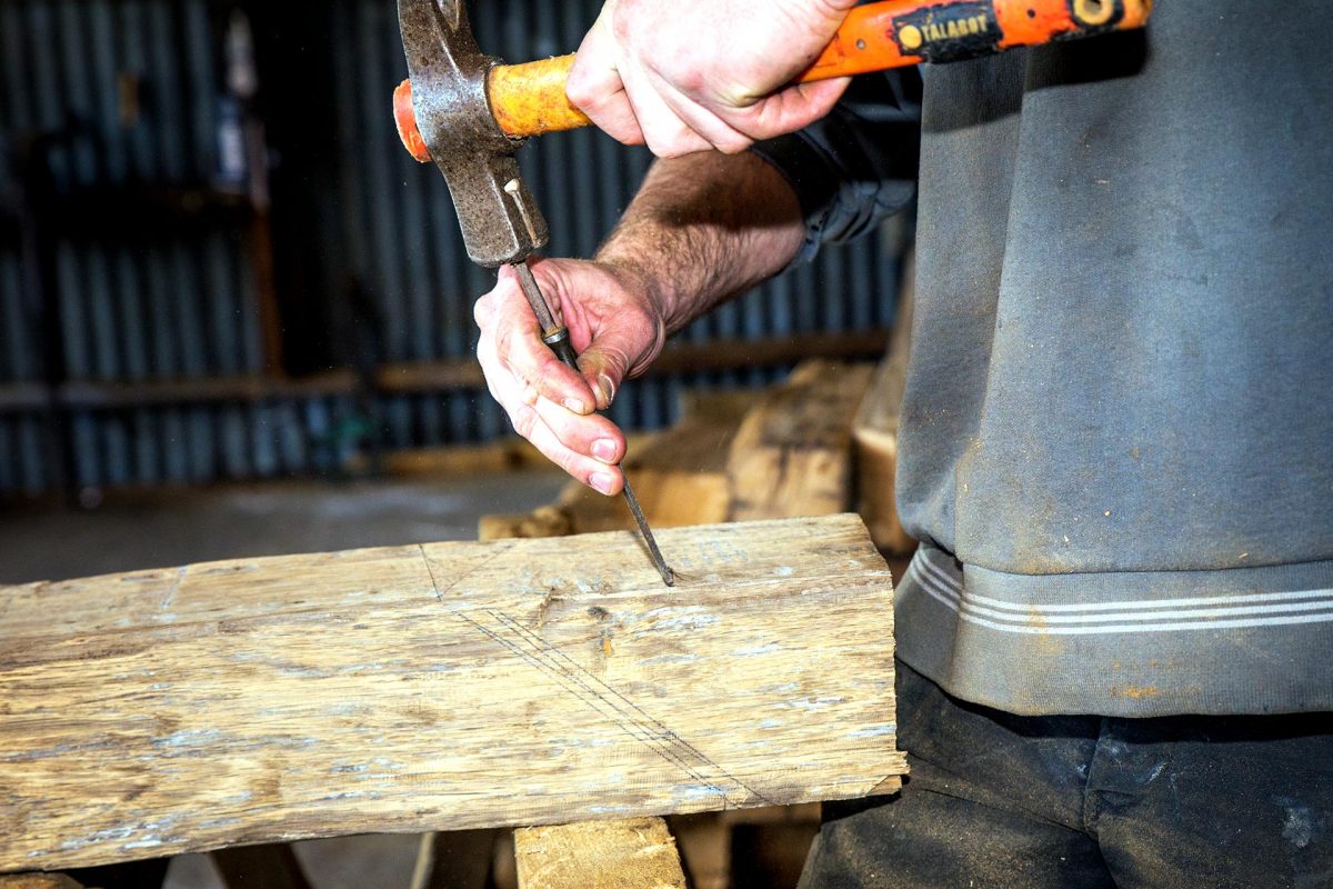 Un charpentier rénove une pièce de bois avec ses outils